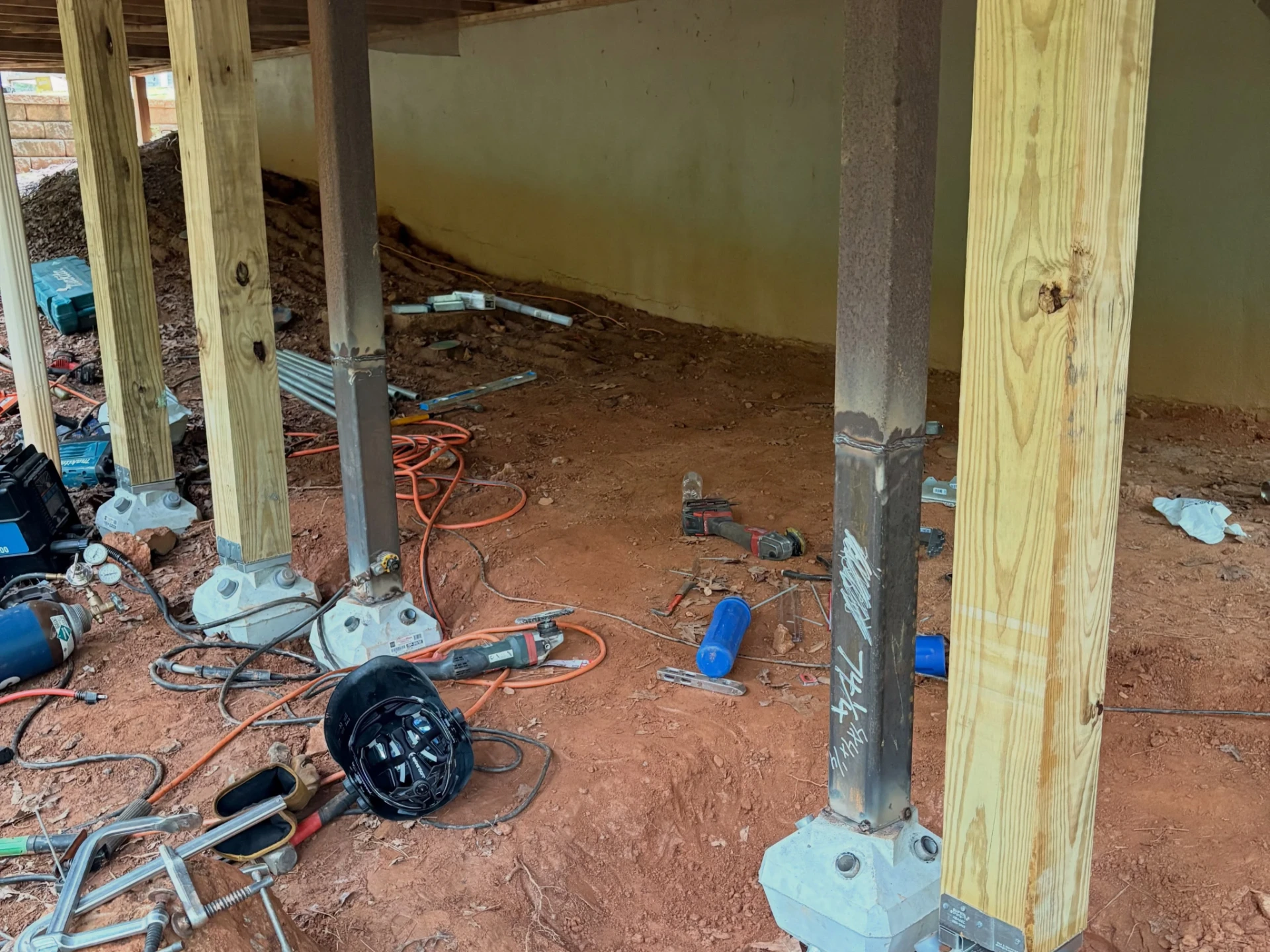 Steel and wooden deck supports standing on concrete footings with welding equipment nearby