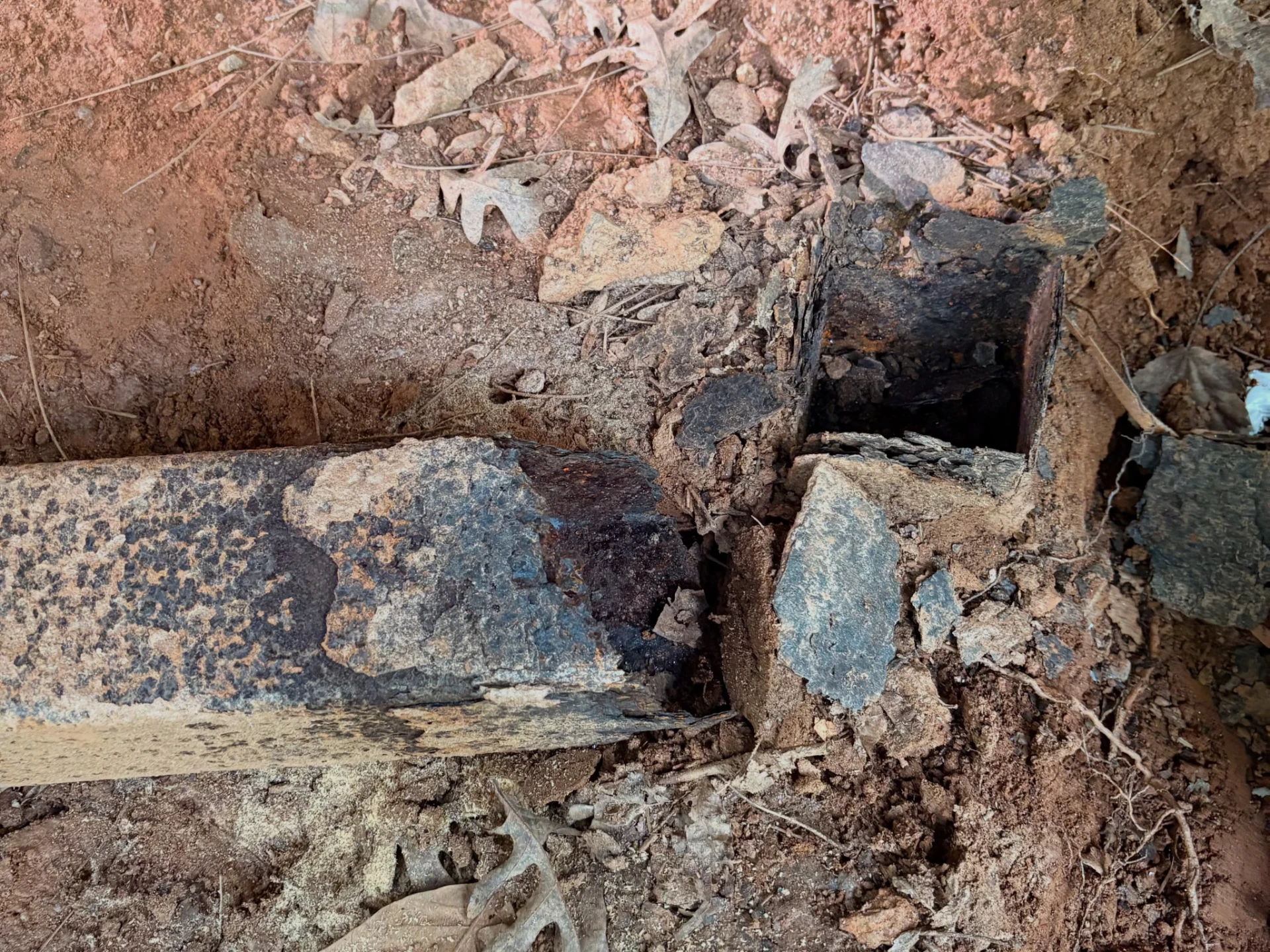 Close view of a deteriorated deck support base and broken material exposed at ground level