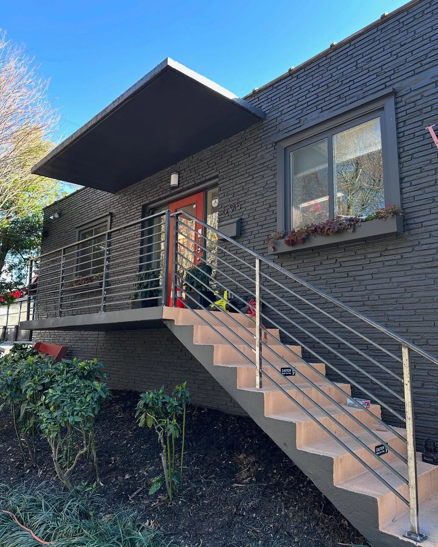 Finished horizontal bar steel railings along the entry stairs on a sunny day with tools on the steps