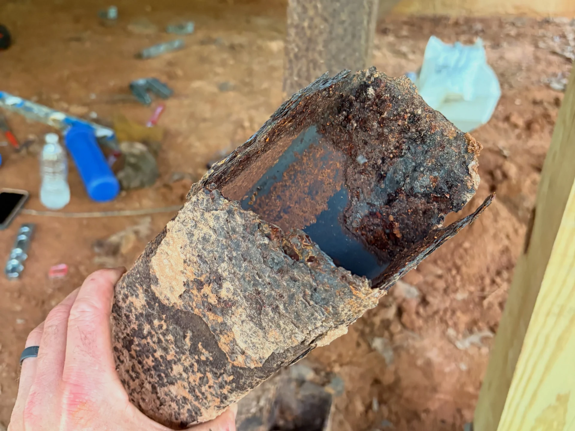 Close view of a removed hollow steel support section with heavy rust and damaged edges