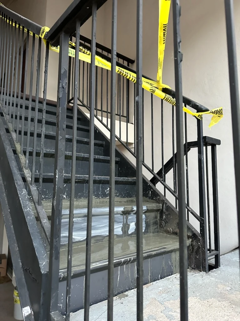 Steel staircase and railings cordoned off with yellow caution tape during stair tread repairs