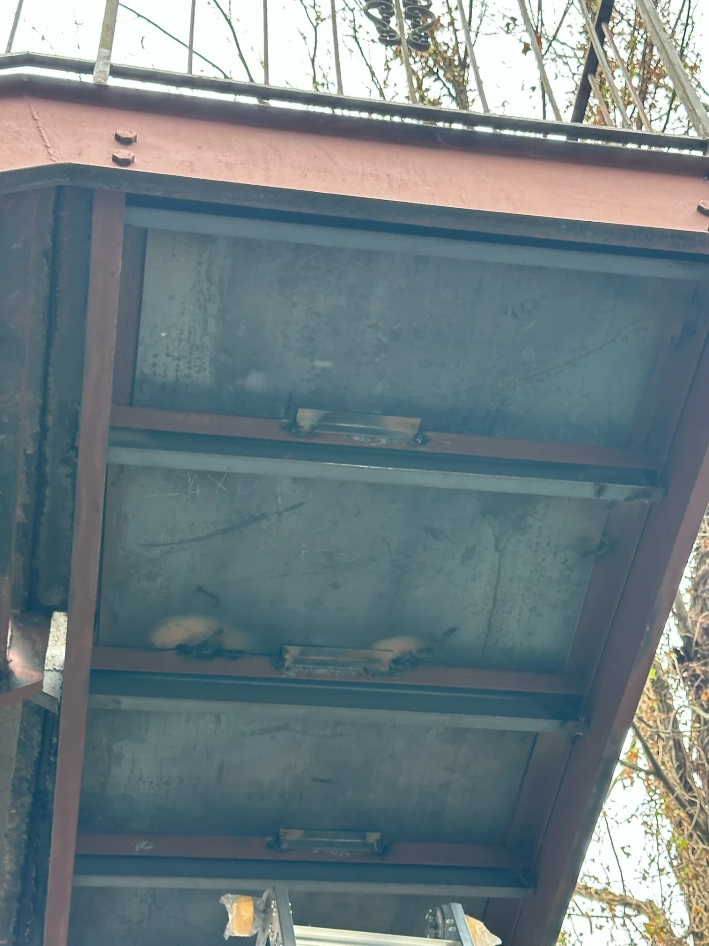 View beneath an exterior steel staircase showing tread pans and supporting steel framing