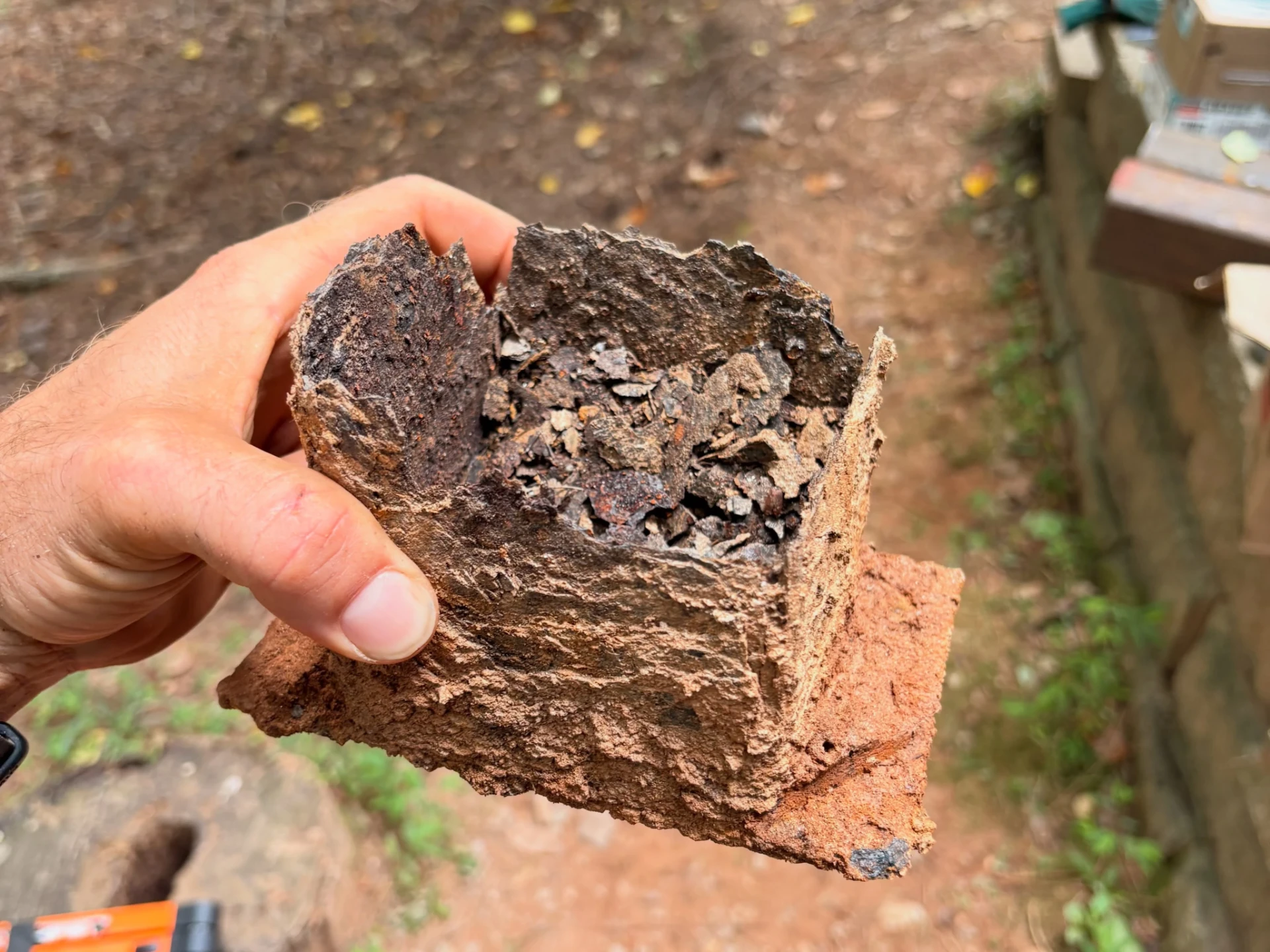 Hand holding a removed deck support section with severe deterioration at the end
