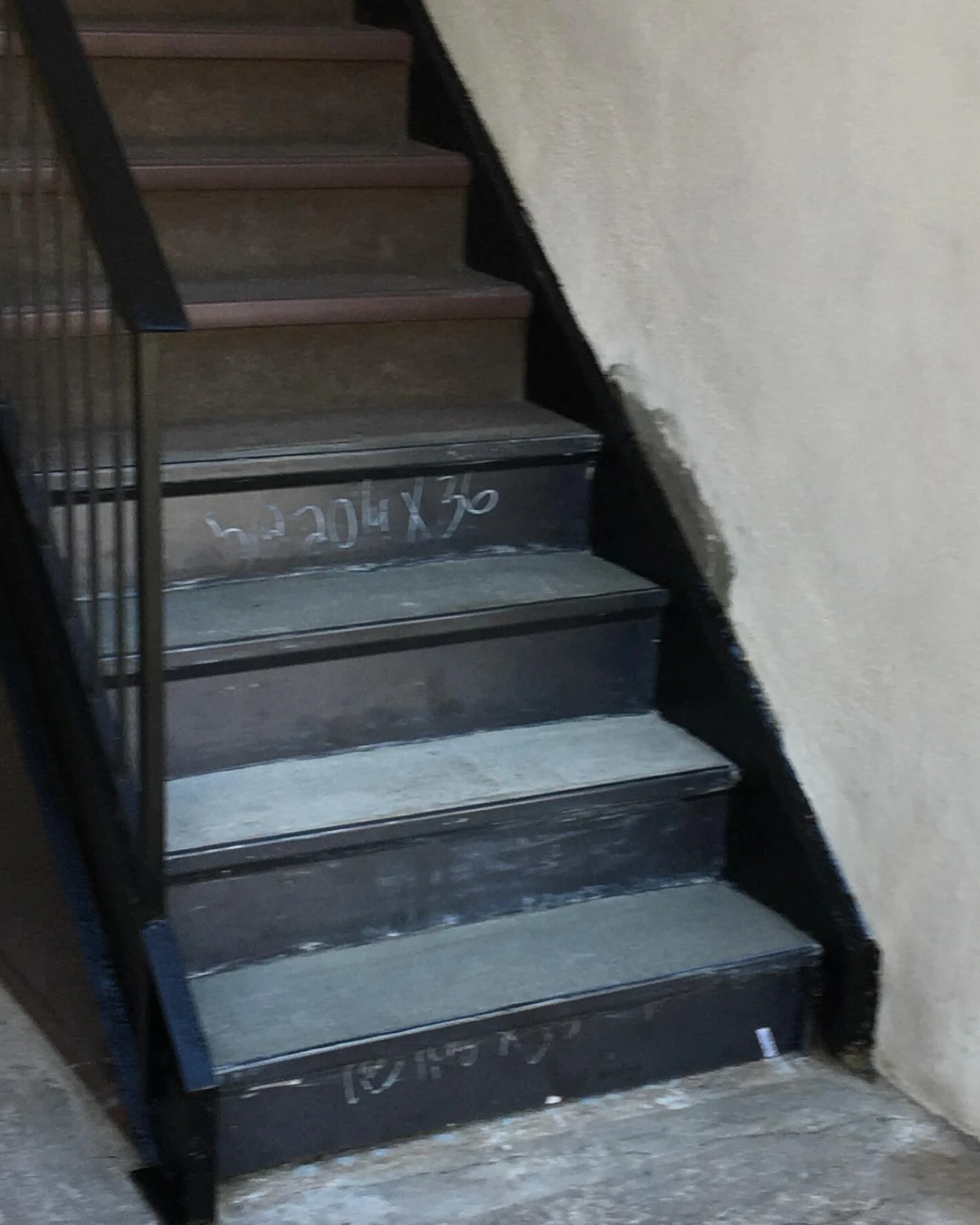 Repaired steel staircase with replacement tread pans fitted between the existing stair railings